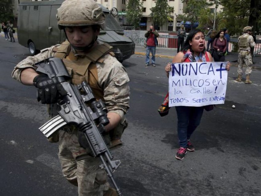 A woman holds a sign saying "No soldiers on the streets". Phot: Chile Solidarity Network/Twitter